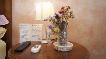 Una mesa con un jarrón de flores, un control remoto y un cartel con texto.