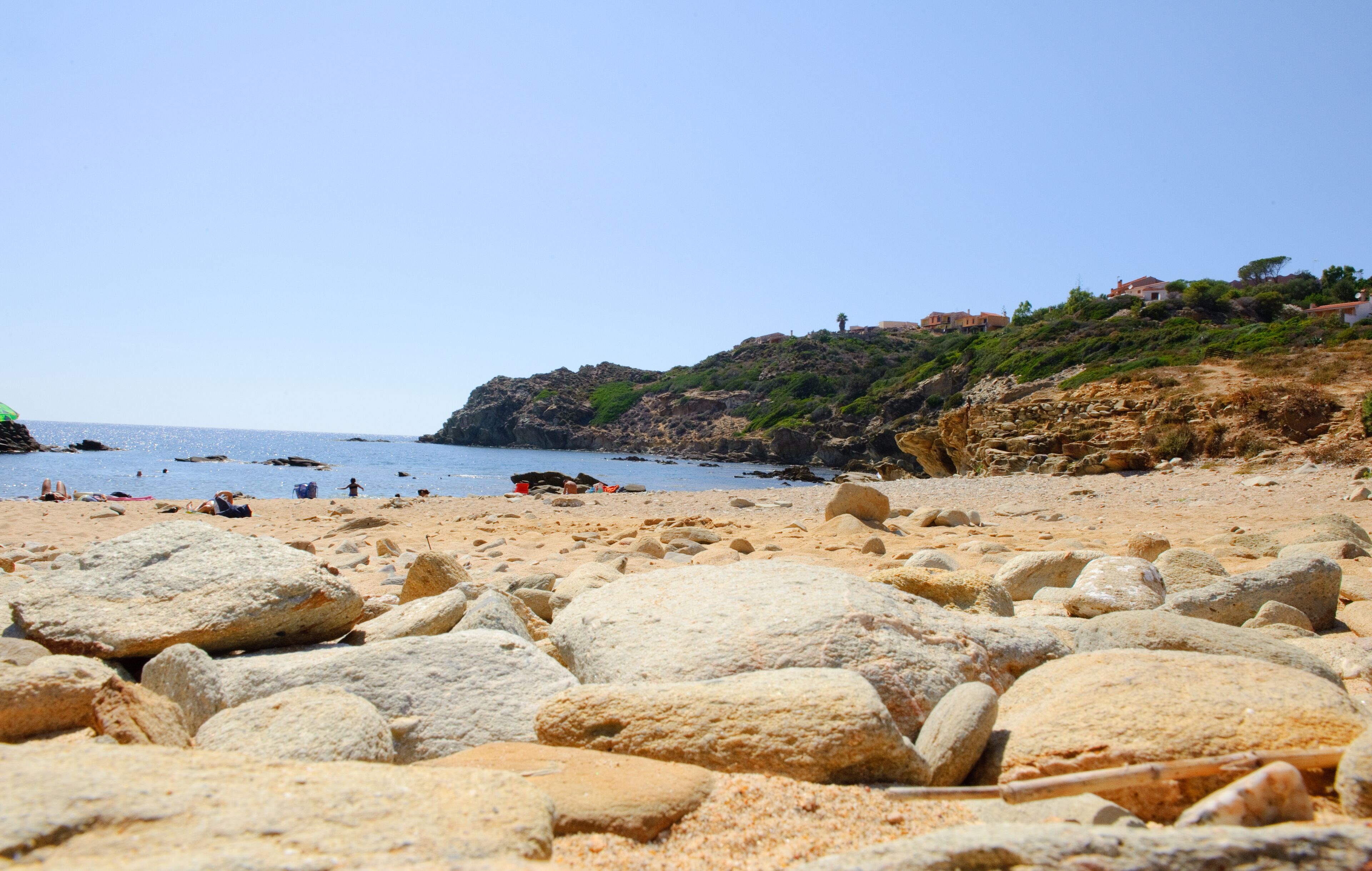 Une plage rocheuse parsemée de gros rochers, offrant une vue dégagée sur la mer.