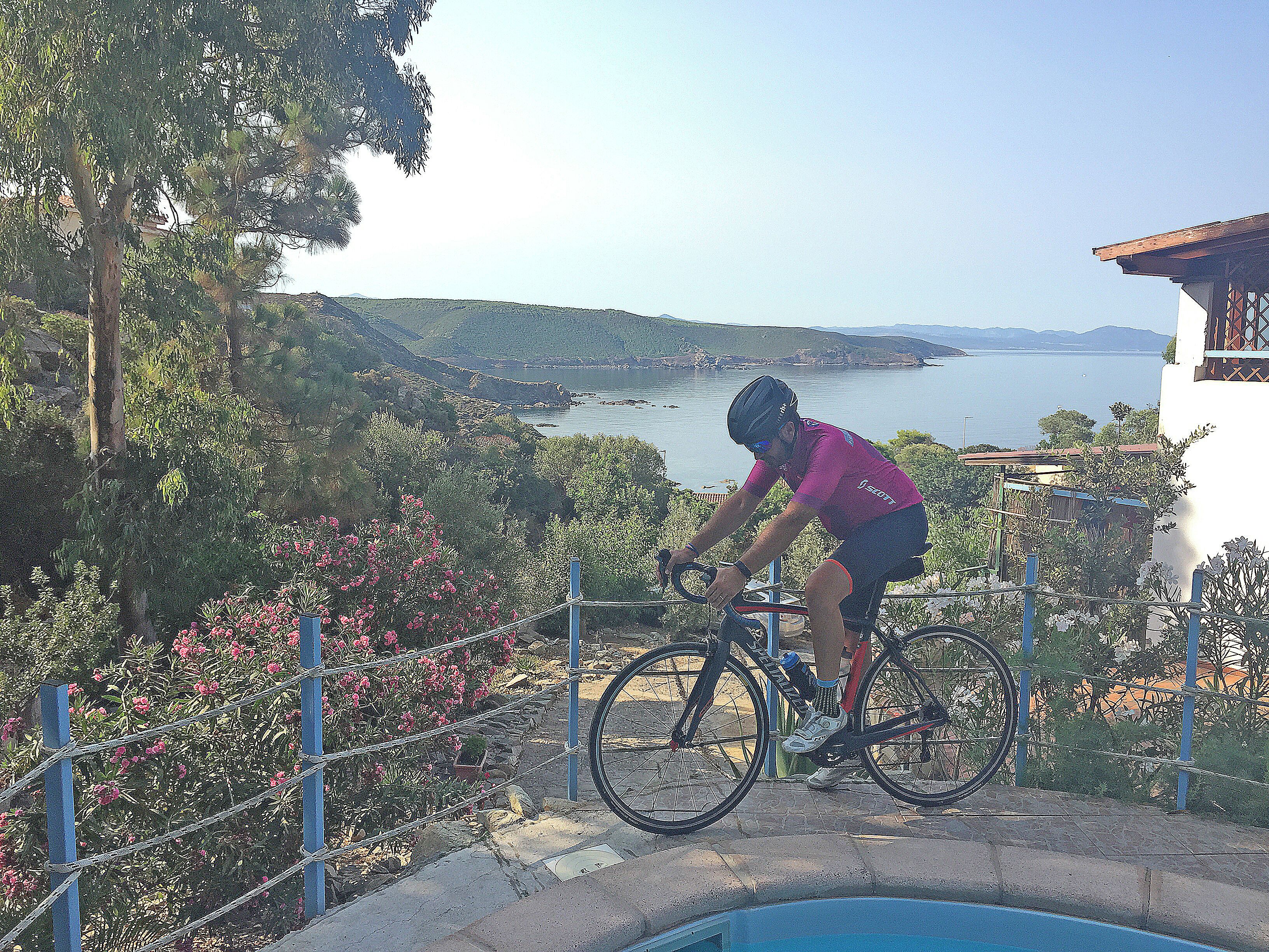 Ein Radfahrer auf einem Radweg mit einem malerischen Seeblick und Hügeln im Hintergrund.