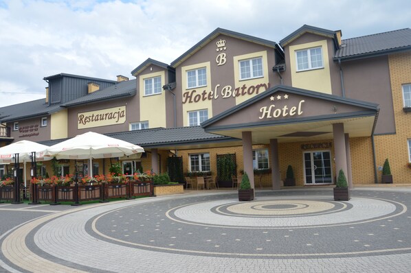 Hotel Batory offers a welcoming entrance with a covered walkway and outdoor seating areas.