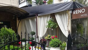 A hotel entrance with a black iron gate, a white awning, and a sign that reads "RENO HOTEL". - Reno (Odesa)