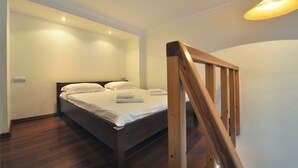 A bedroom with a wooden bed, white linens, and a wooden staircase. - Reno (Odesa)