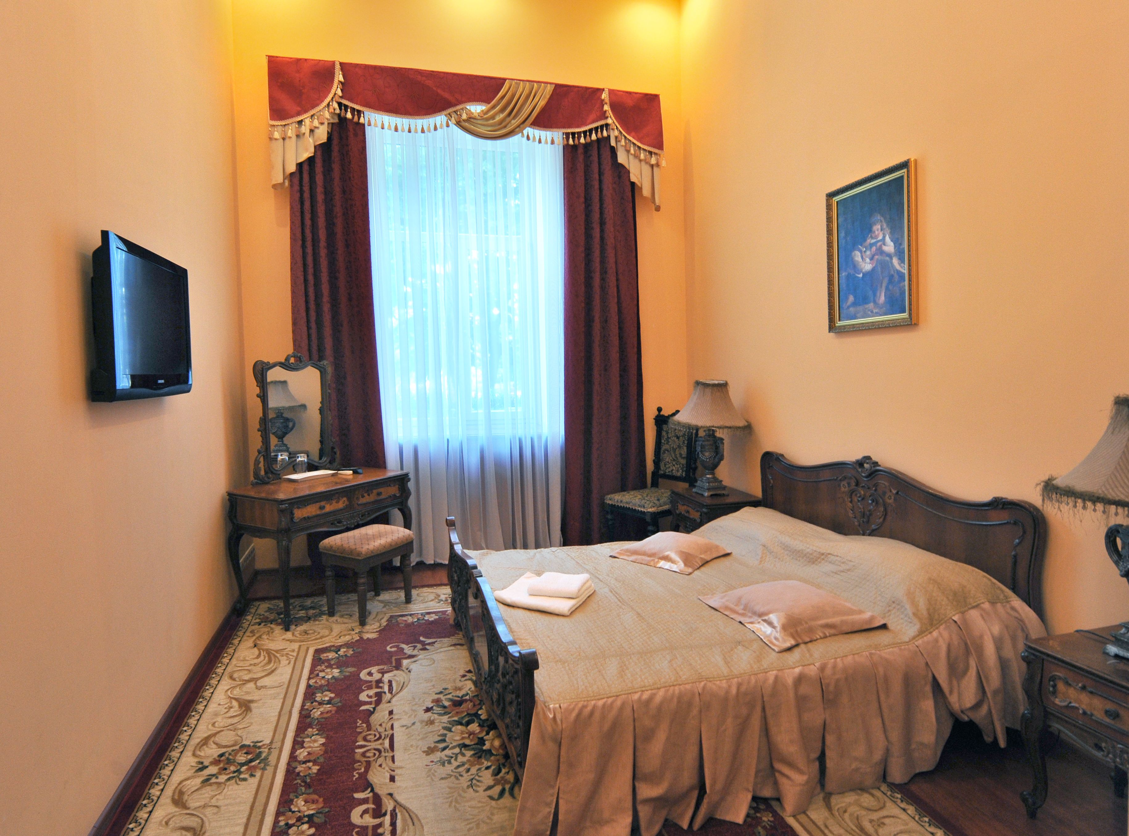Habitación de hotel con cama, escritorio, silla, televisor y un cuadro en la pared.