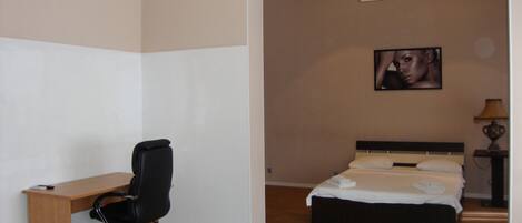 Un dormitorio con cama, escritorio y silla.