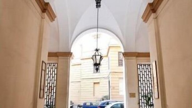 A hallway with a high ceiling, arched design, and a hanging light fixture. - La Maison de Marta (Rome)