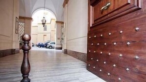 A marble-floored hallway with a wooden door featuring metal studs. - La Maison de Marta (Rome)