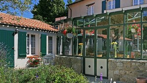 A conservatory with a glass roof, stone walls, and potted plants. - Domaine Le Martinet, The Originals Relais  (Bouin)