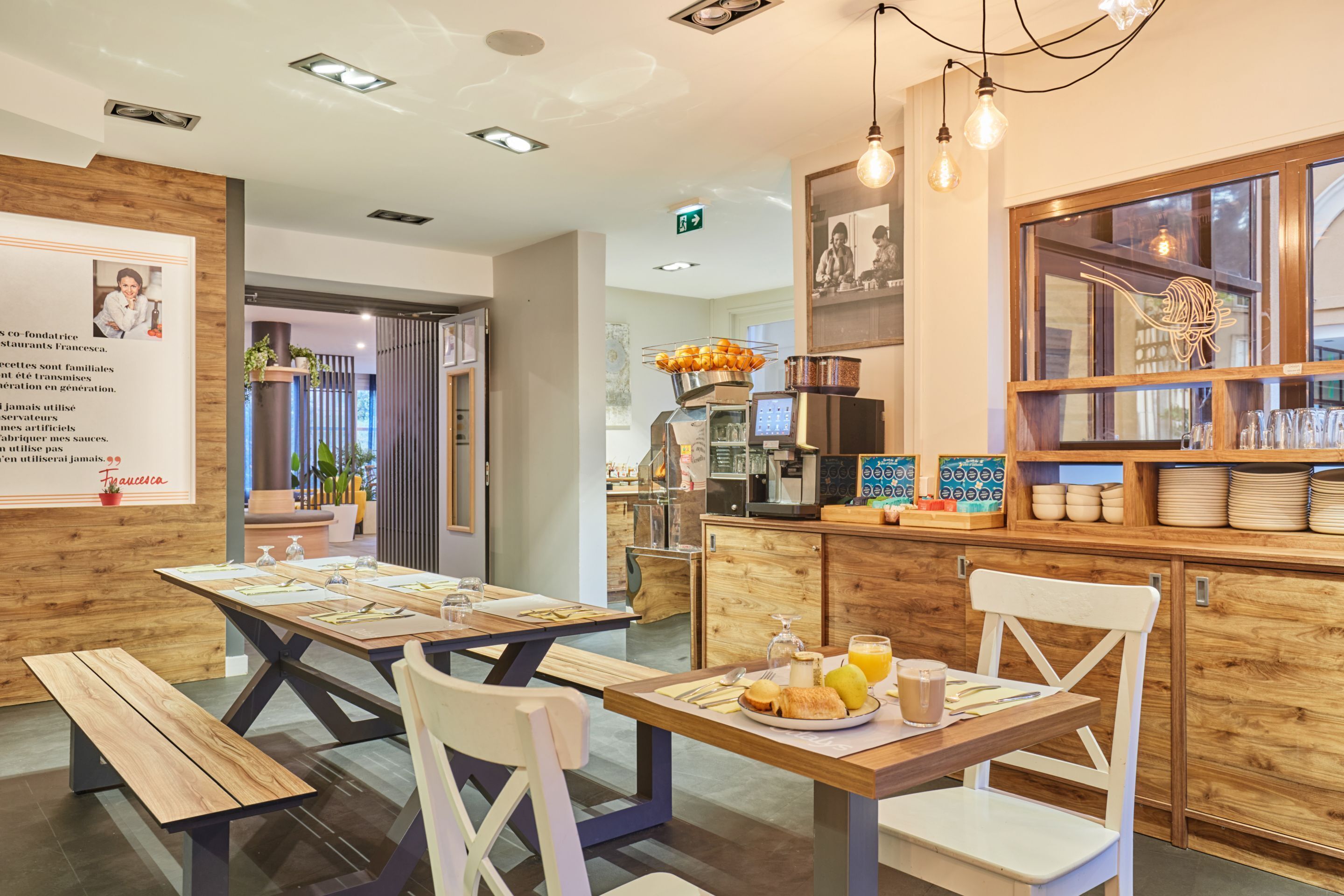 A restaurant with wooden tables and chairs, a bar area with a display of plates and glasses, and a menu board on the wall.