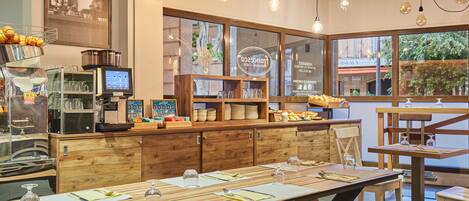 Un restaurant avec des meubles en bois, un comptoir équipé de matériel de cuisine et de grandes fenêtres.