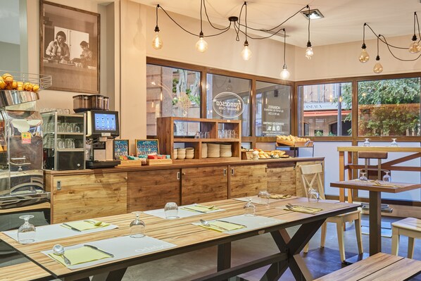 Ein Restaurant mit Holztischen, einer Theke mit Küchenausstattung und großen Fenstern.