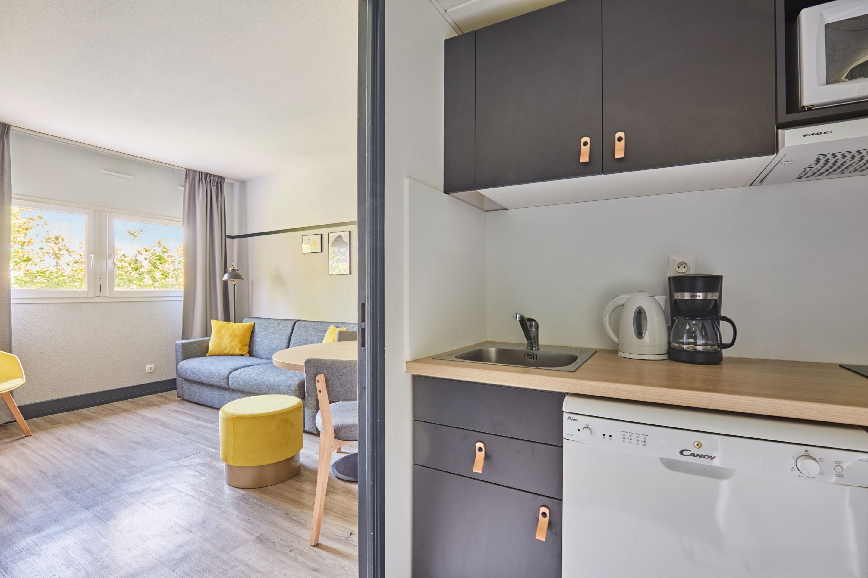 A compact kitchen with a dishwasher, a coffee maker, and a microwave.