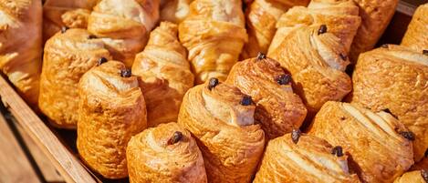A display of assorted pastries, including croissants and chocolate-filled pastries, arranged in a wooden case.