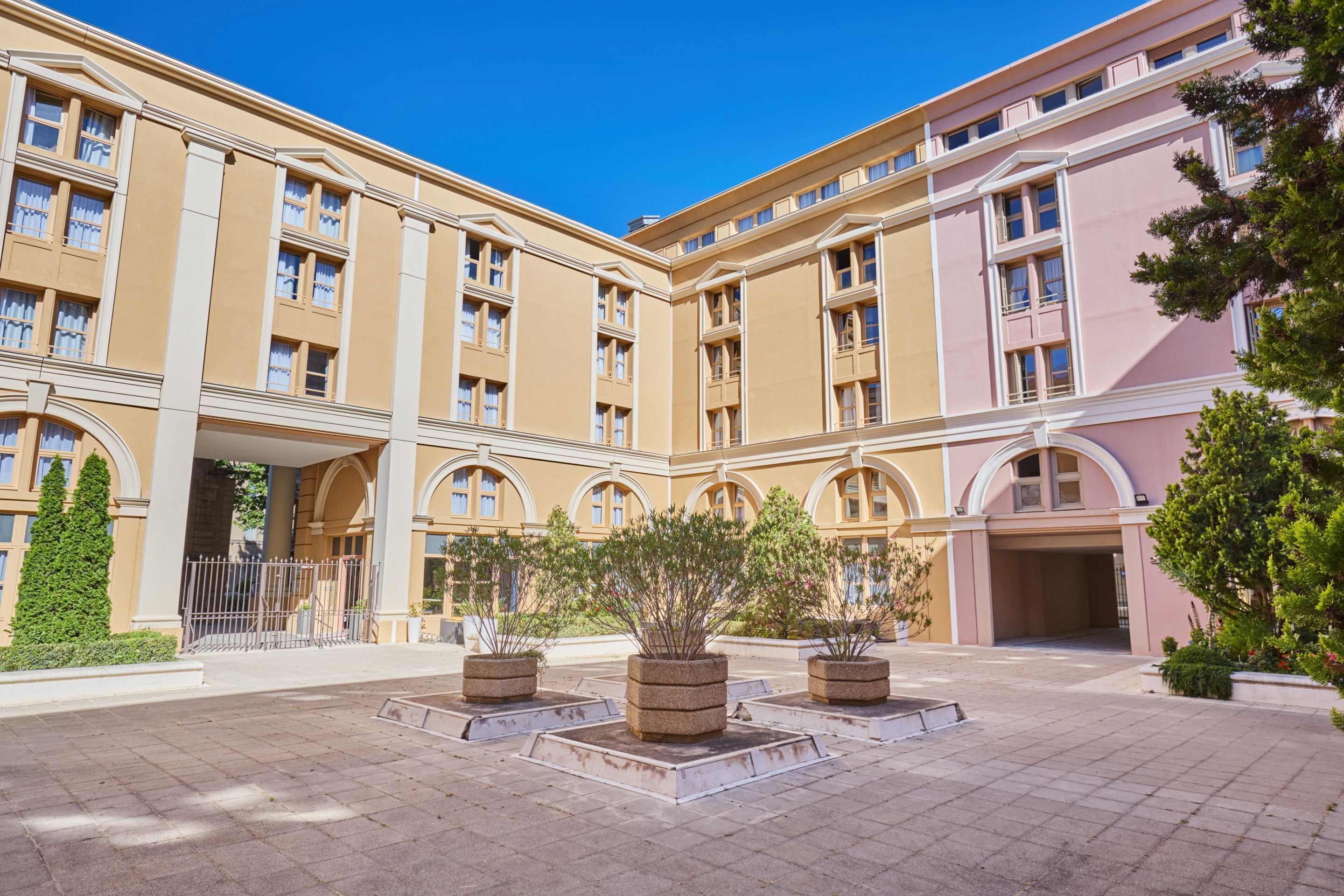 Un edifici gran de diverses plantes amb una façana simètrica, nombroses finestres i un pati central amb jardineres.