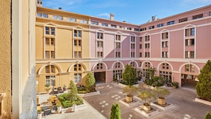 A multi-story hotel with a central courtyard, outdoor seating, and a symmetrical facade with arched windows. - Odalys City Apartment Hotel - Aix en Provence Centre Palais des Congrès (Aix-en-Provence)