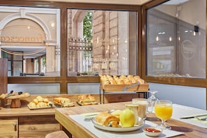 Ein Frühstücksbuffet mit Gebäck, Früchten und Getränken.