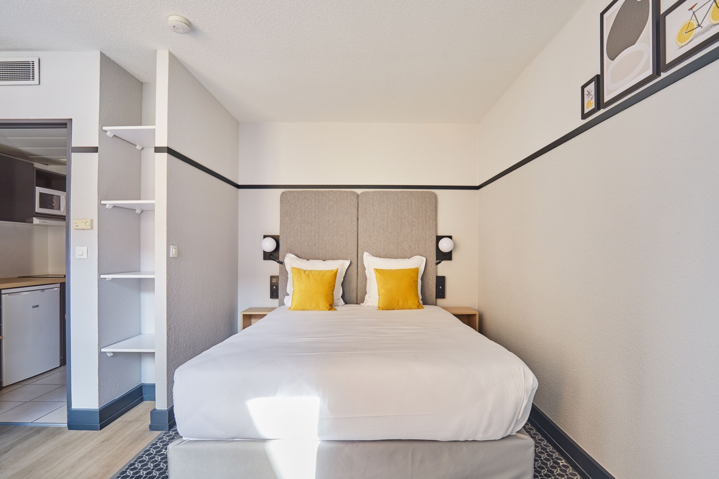 Una camera d'albergo con un letto grande, due comodini, una testiera e un armadio a muro.