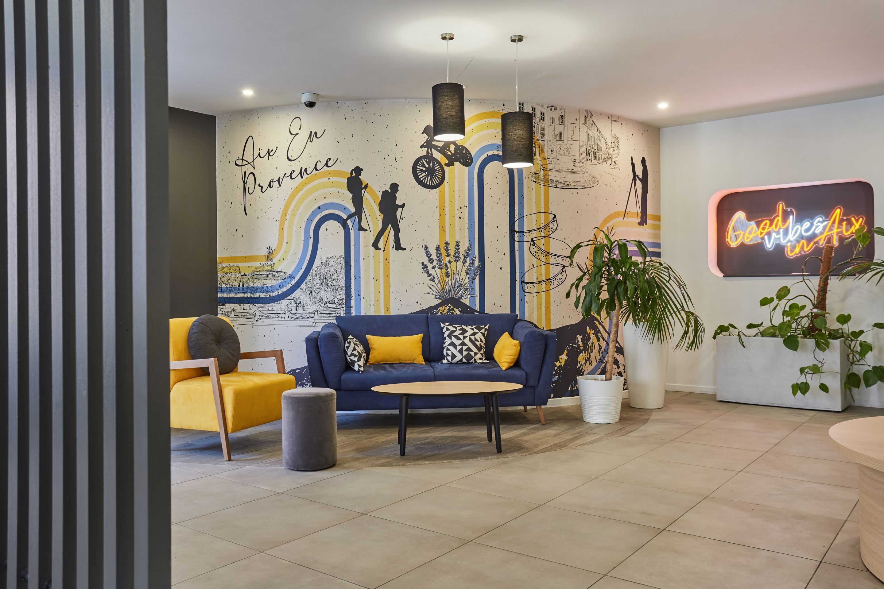 Un espace de détente moderne avec un canapé bleu, un fauteuil jaune et une table ronde.
