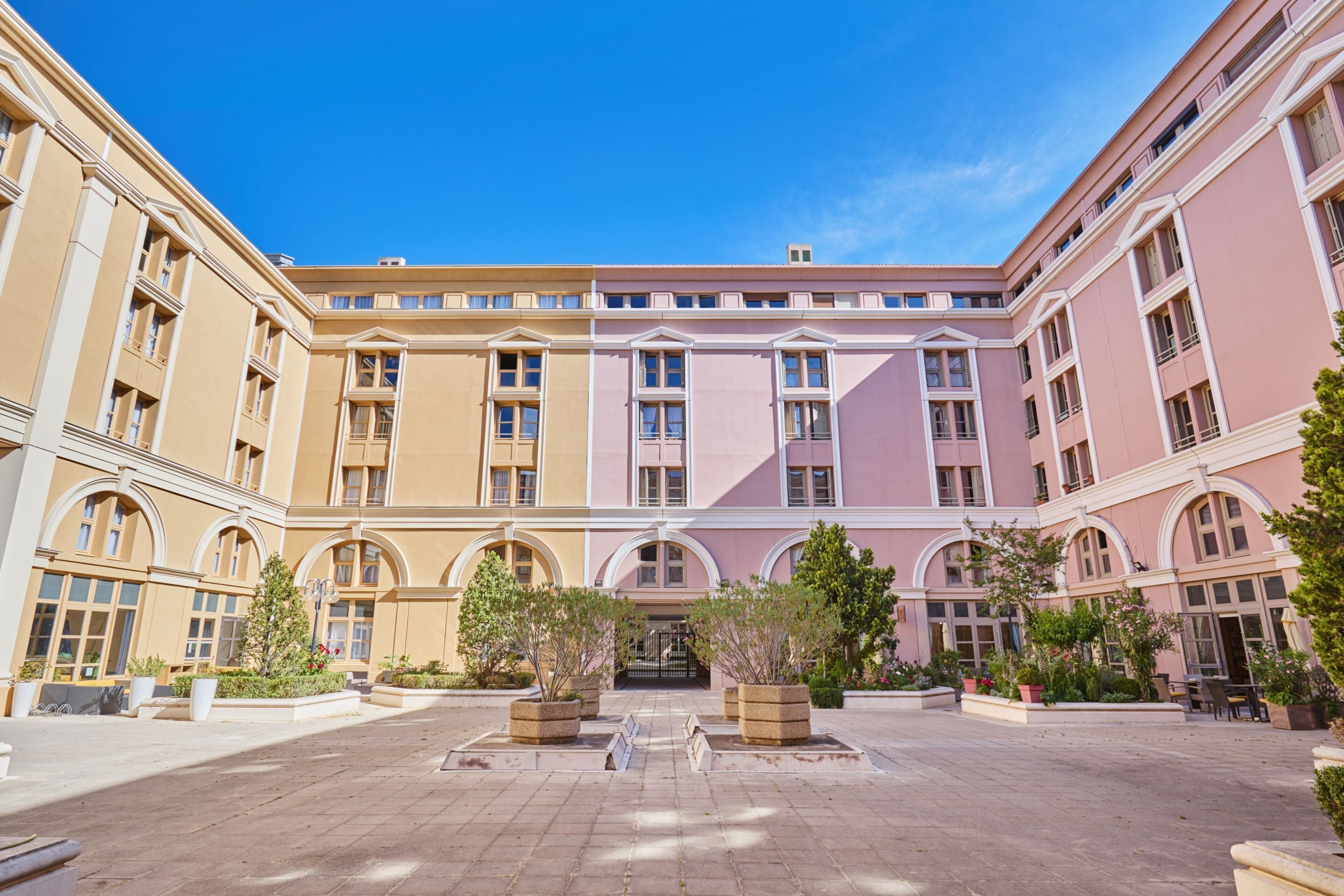 A courtyard with a central fountain, surrounded by buildings with arched windows and balconies.
