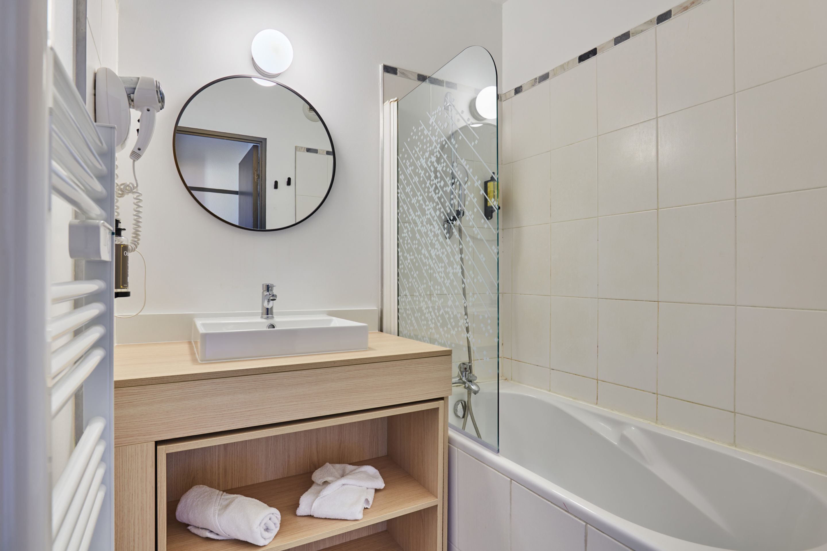 A modern bathroom with a sink, mirror, and glass shower enclosure.