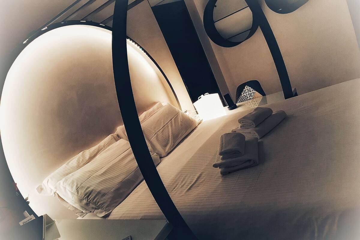 A bed with a canopy, a bedside table with a remote control, and a neatly folded towel on the bed.