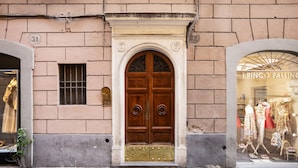 Un edificio con una puerta grande de madera, un ventanal pequeño y un escaparate que muestra ropa.