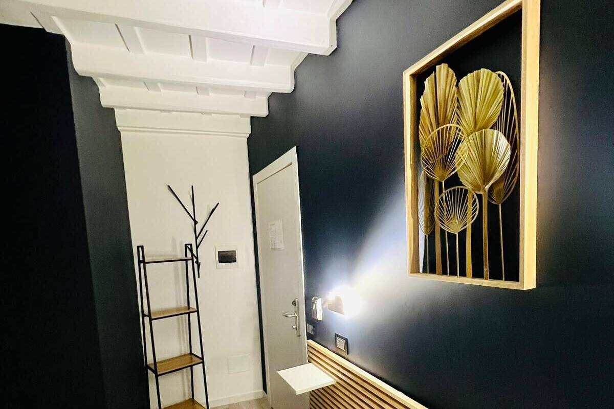 A modern hotel room with a bed, a wooden bedside table, a mirror, and a wall-mounted decorative piece.