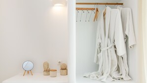 Un baño con tocador de madera, espejo redondo y perchero para bata.