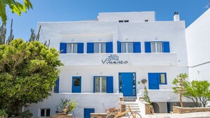 Edificio blanco con contraventanas azules y un cartel que dice 'Vineyard'.