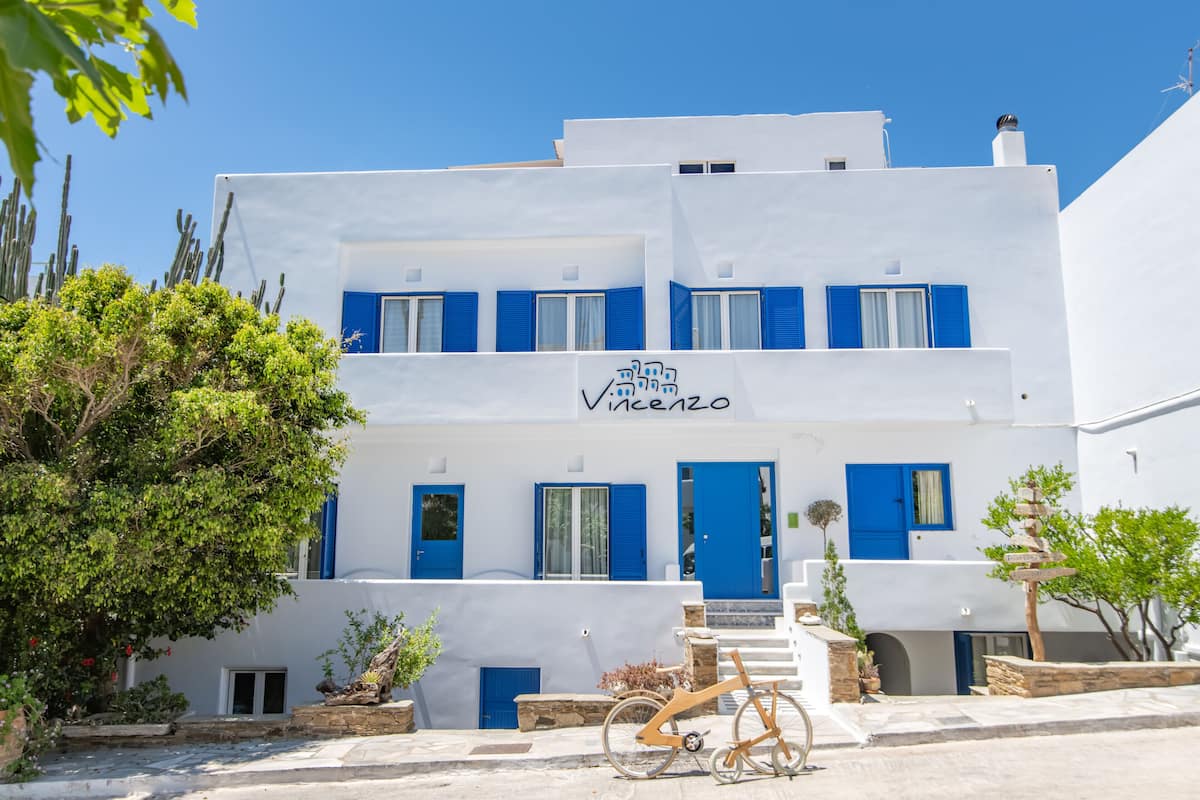 A white building with blue shutters and a sign that reads "Vineyard."