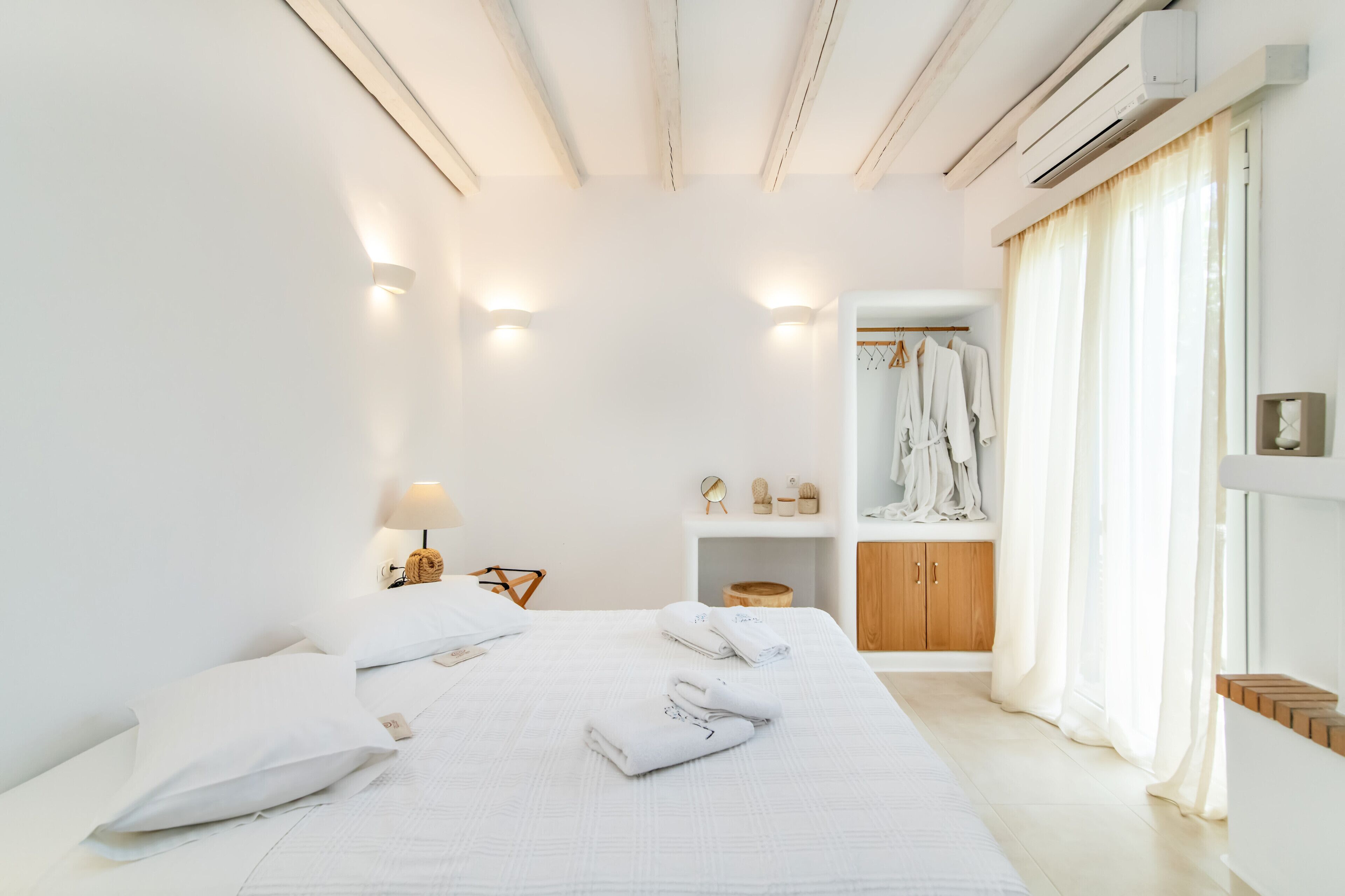 Un dormitorio moderno con una cama grande, lámparas de noche, un aparador de madera y un armario empotrado.