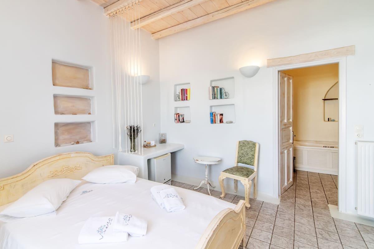 A bedroom with a bed, bedside tables, a chair, and a small desk with books and a bicycle model.