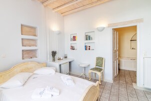 Un dormitorio con cama, mesitas de noche, una silla y un escritorio pequeño con libros y una réplica de bicicleta.