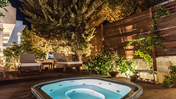 Tinaco en un área exterior bien iluminada con terraza de madera, sillas de descanso y plantas en macetas.