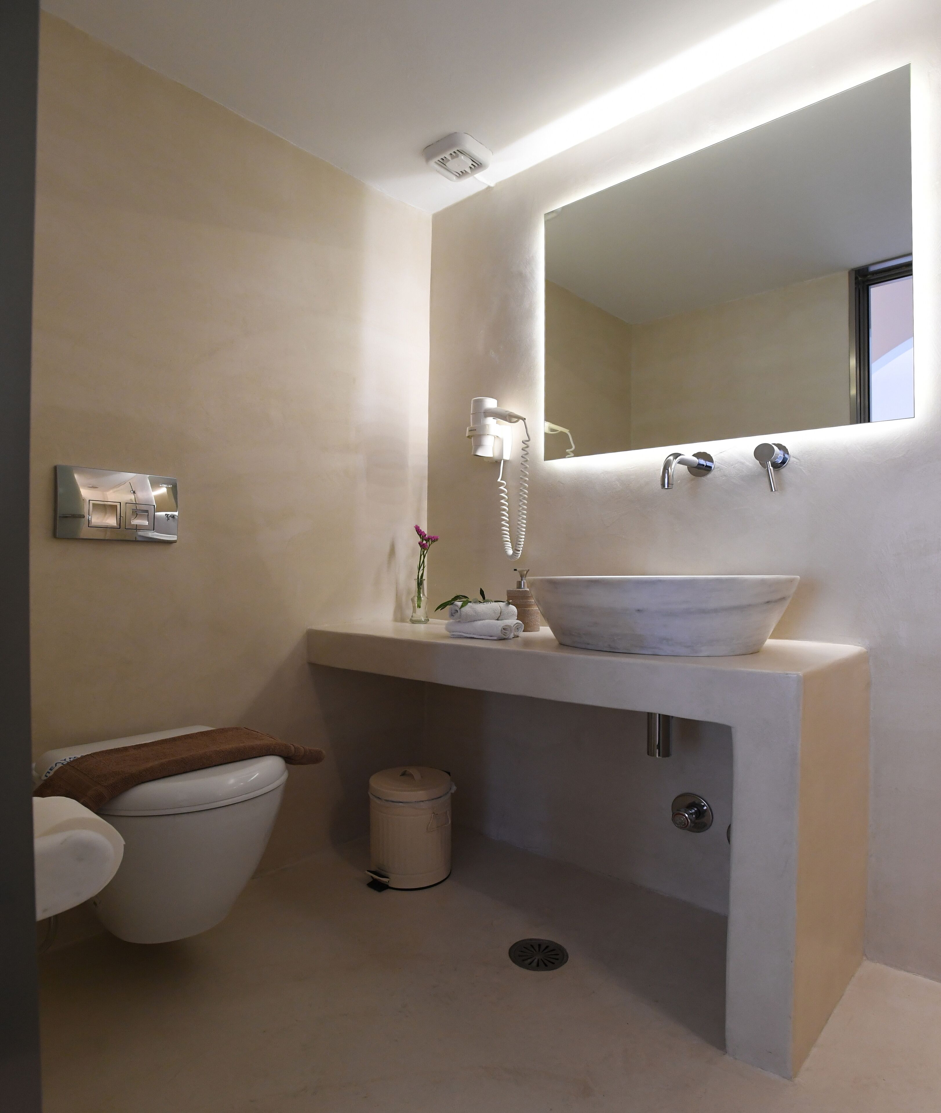 Un baño moderno con lavamanos empotrado, inodoro y espejo.