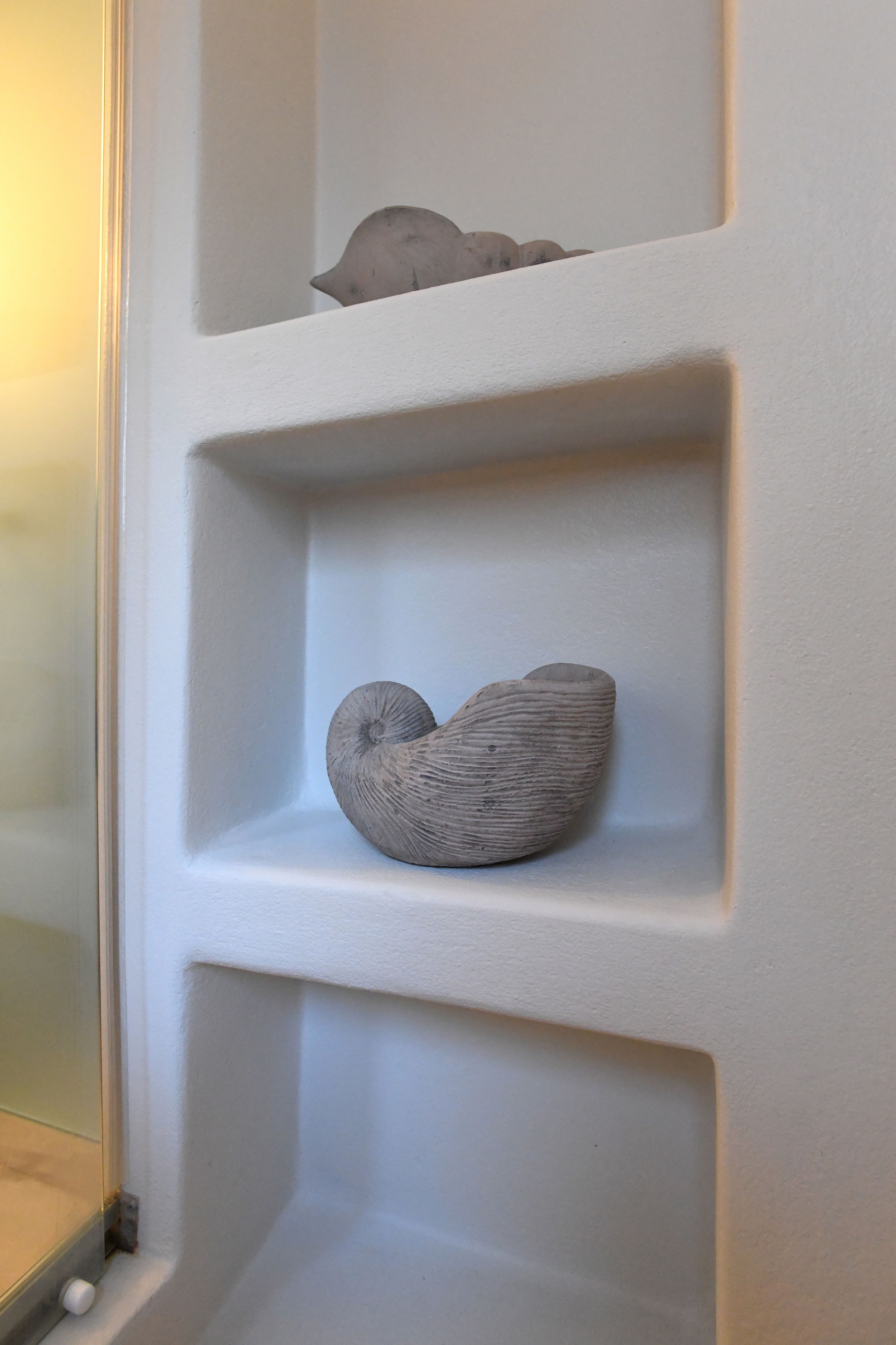 A white shelf unit with three compartments, each containing a different textured object.