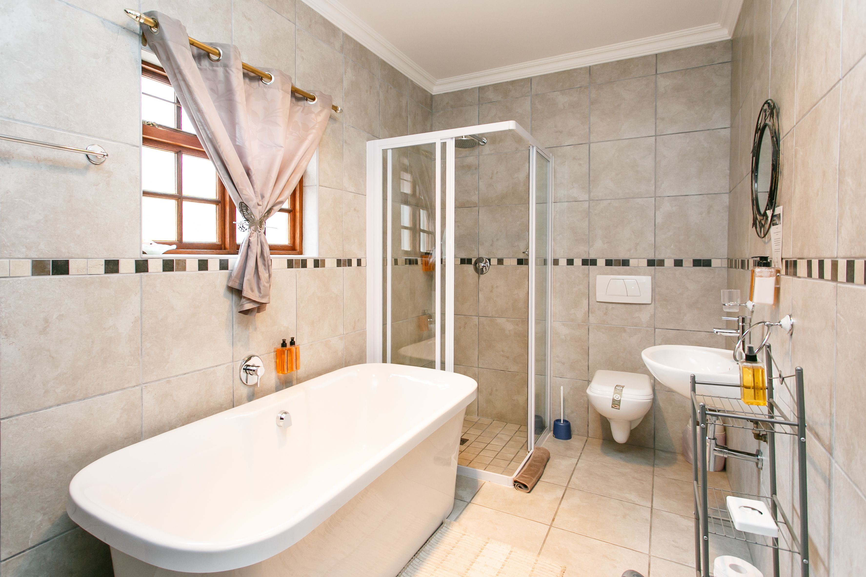 Ein modernes Badezimmer mit einer freistehenden Badewanne, einer gläsernen Dusche, einer Toilette und einem Waschbecken mit Handtuchhalter.