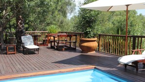 A wooden deck with a swimming pool, surrounded by wooden furniture and potted plants. - Gumtree Guest House (Oudtshoorn)