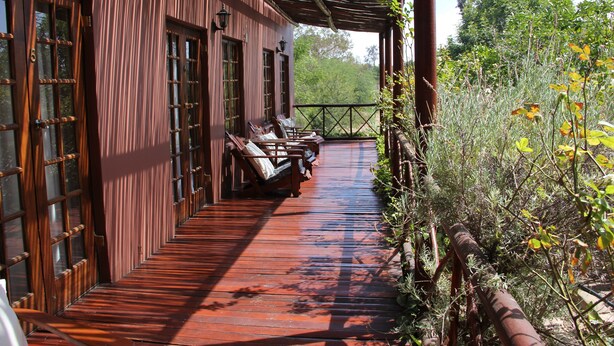 A wooden building with a covered porch, a bench, and a railing. - Gumtree Guest House (Oudtshoorn)