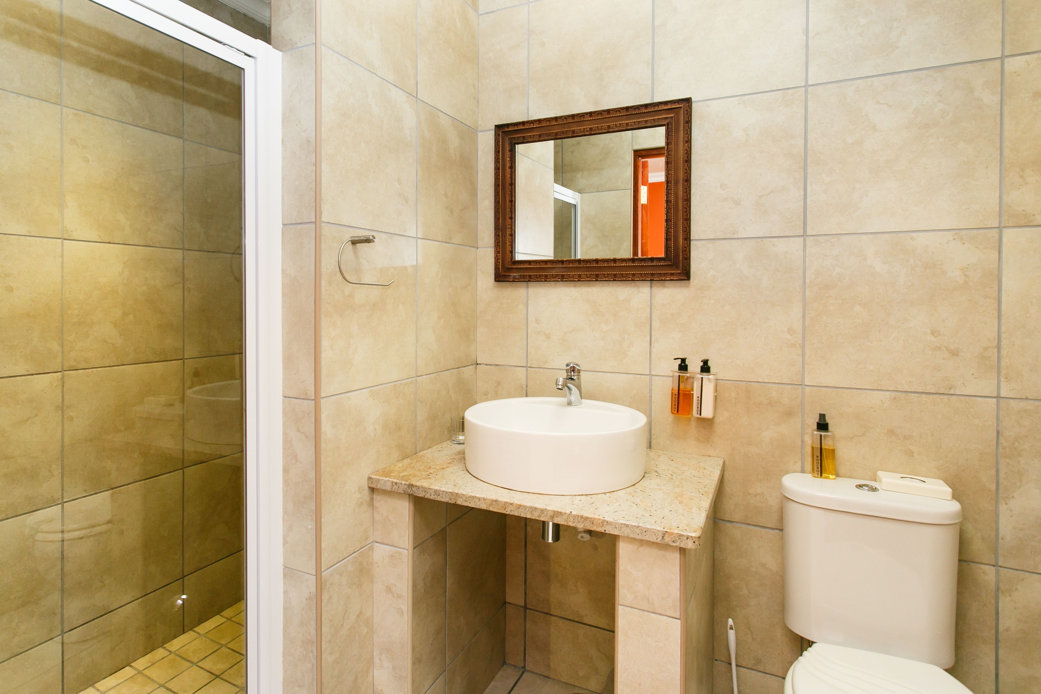 A bathroom with a sink, mirror, toilet, and shower.