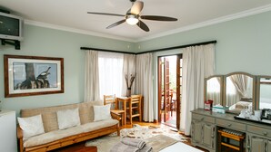 A bedroom with a bed, a wooden sofa, a desk, a chair, a dresser, and a ceiling fan. - Gumtree Guest House (Oudtshoorn)