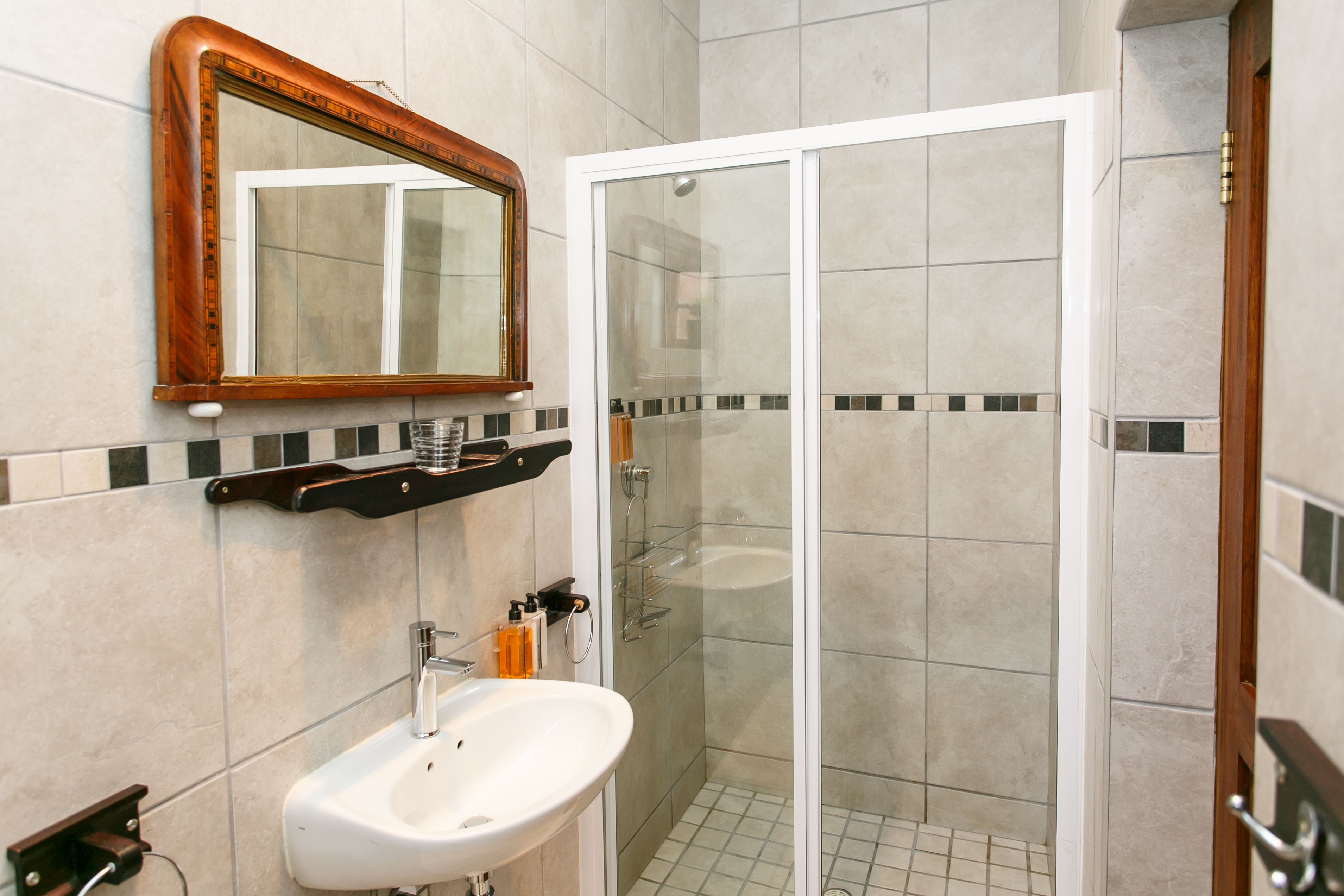 A bathroom with a white sink, a mirror, and a glass-enclosed shower.