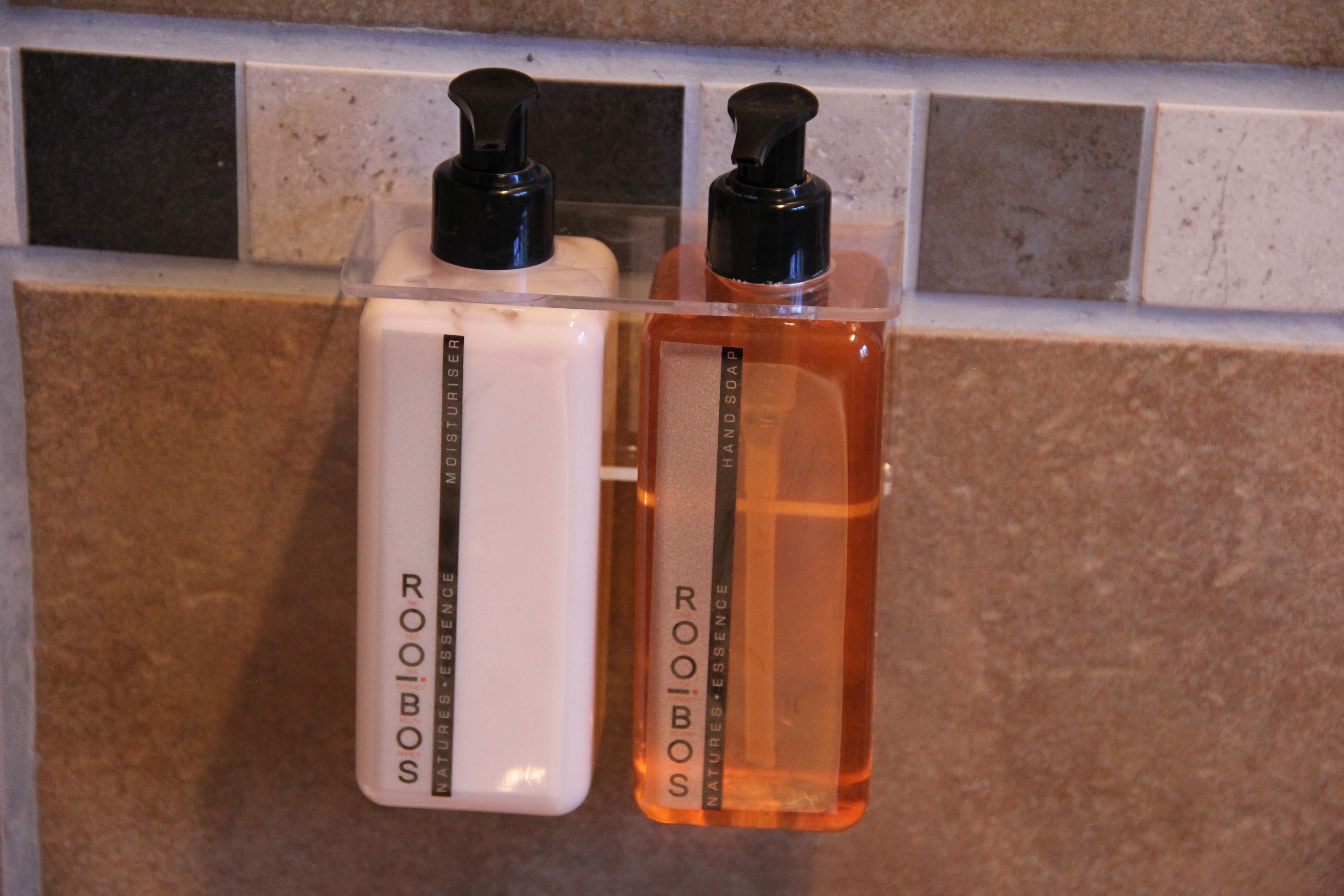 Two bottles of Roobos hand soap on a tiled surface.