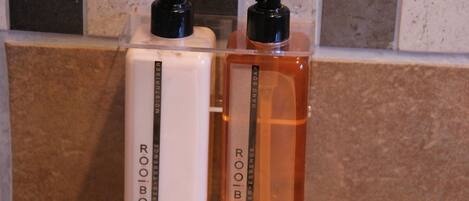 Two bottles of Roobos hand soap on a tiled surface.
