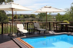 A wooden deck with a swimming pool, surrounded by lounge chairs and umbrellas. - Gumtree Guest House (Oudtshoorn)