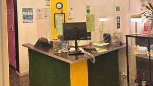 A reception desk with a chandelier, a clock, and a sign reading "BARBIERI SOL". - Barbieri Sol Hostel (Madrid)