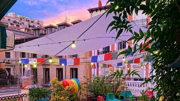 An outdoor patio with tables and chairs, surrounded by potted plants and colorful decorations. - Barbieri Sol Hostel (Madrid)