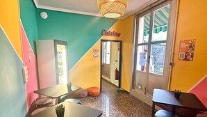 A brightly colored interior with a central table, seating, and a hanging light fixture. - Barbieri Sol Hostel (Madrid)