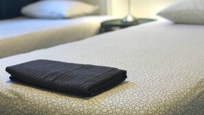 A neatly made bed with a folded dark towel on the lower bed. - Barbieri Sol Hostel (Madrid)