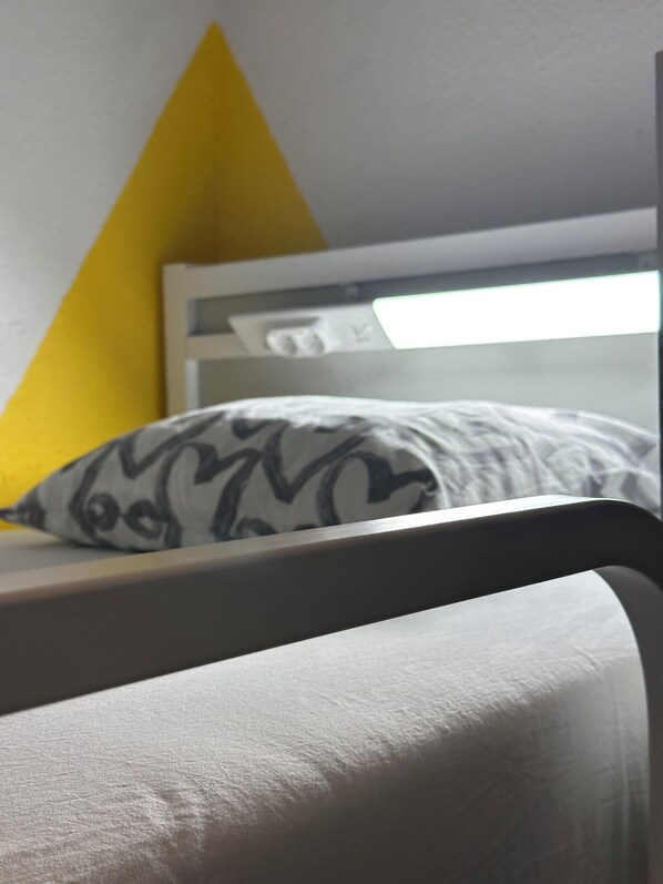 A bunk bed with a white headboard and a pillow with a black pattern.