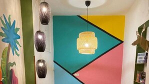 A cozy living room with a black leather sofa, a wooden coffee table, and a colorful geometric wall design. - Barbieri Sol Hostel (Madrid)